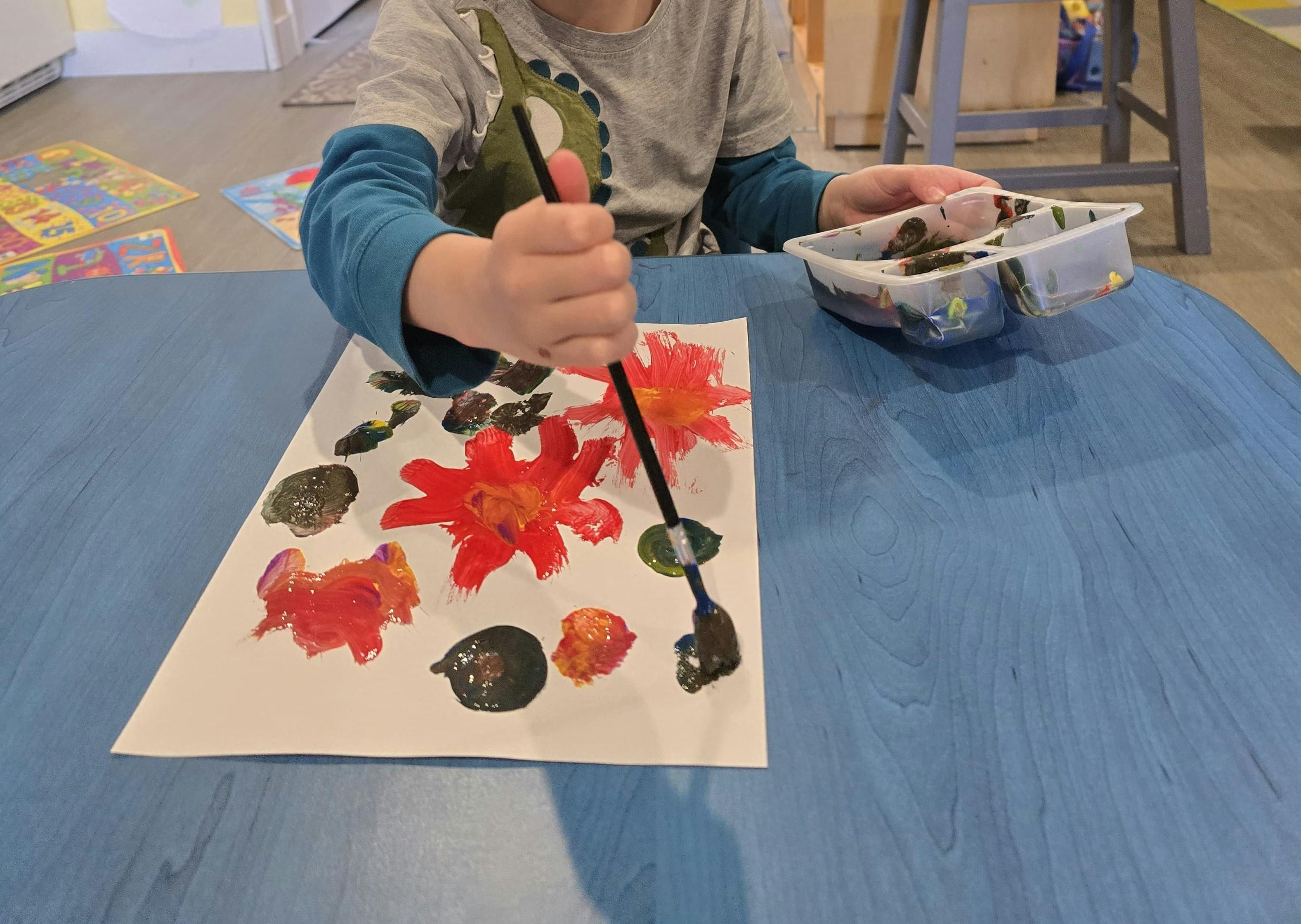 Child painting on paper with a brush