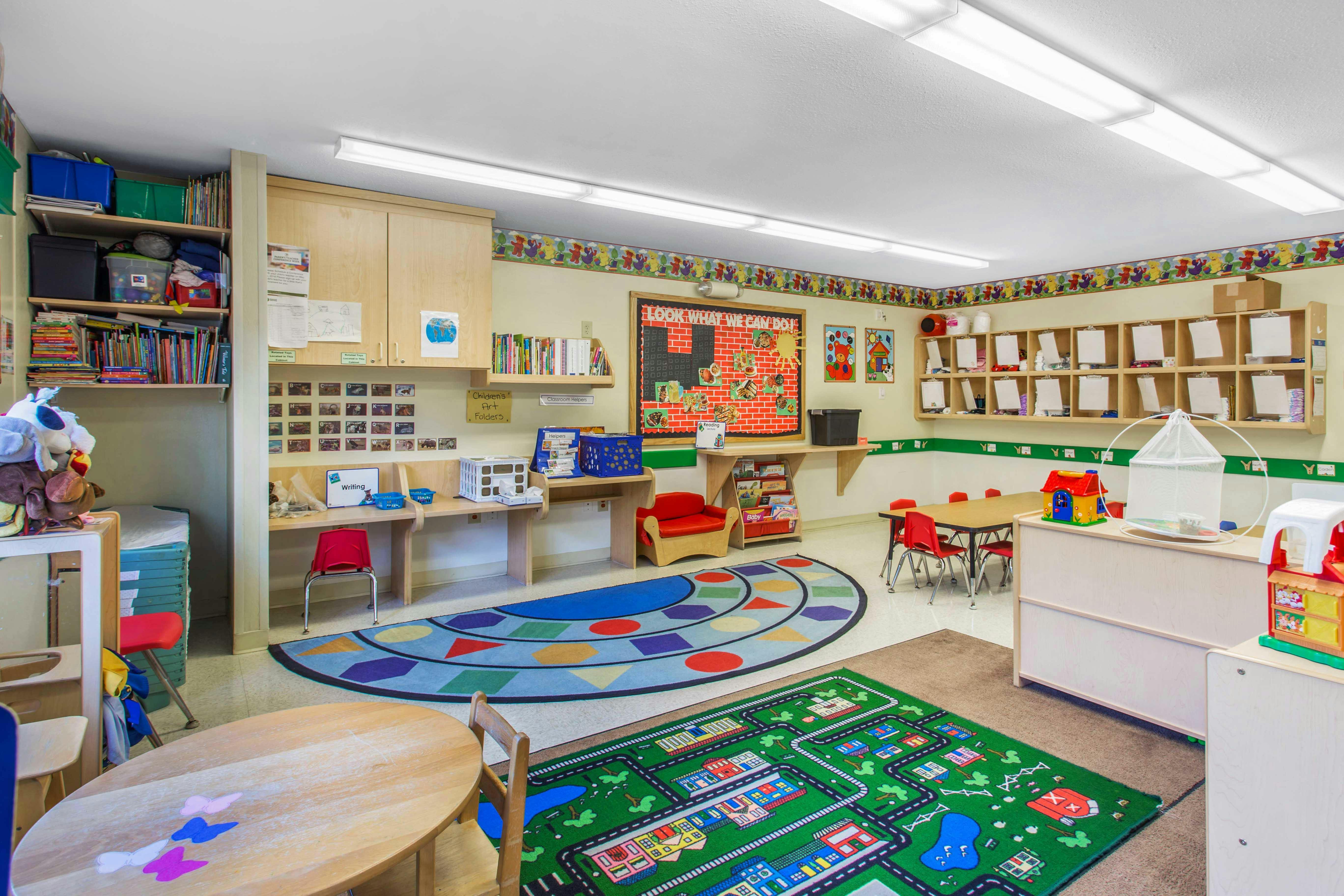 Empty classroom with colorful rugs and small tables