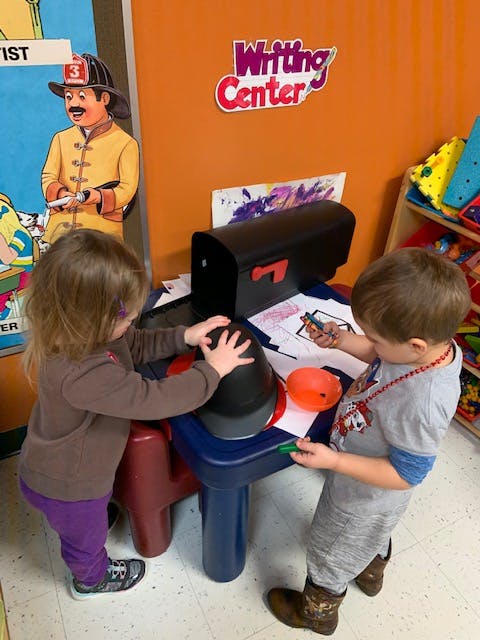 Two children playing at a small table in a classroom