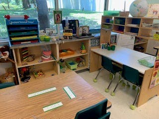 Classroom with small tables and shelves with learning materials