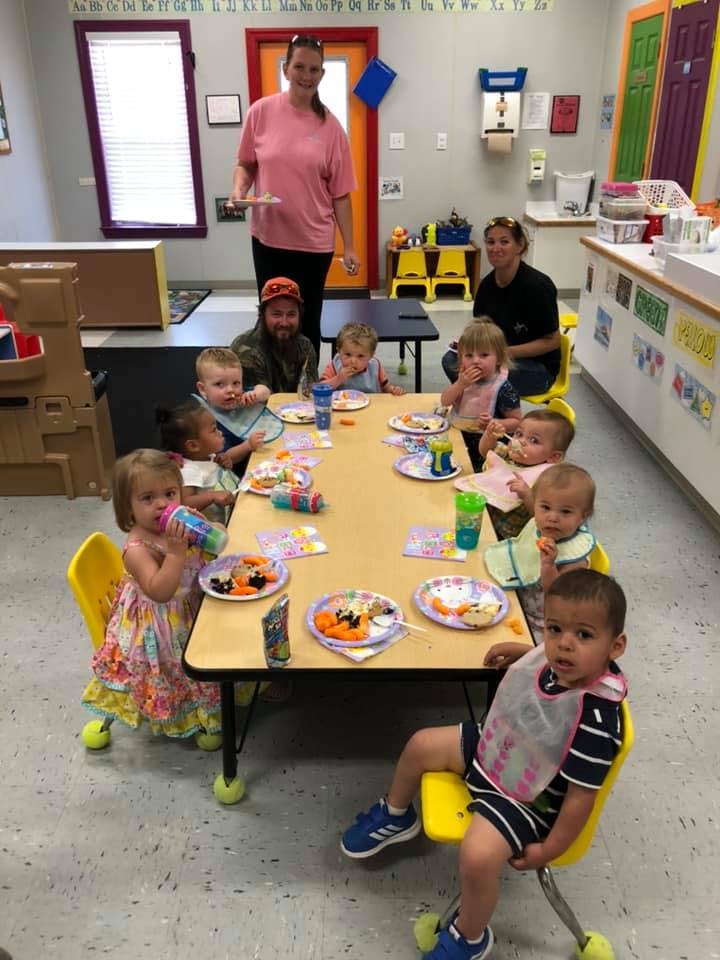 Adults and children eating at tables in a classroom