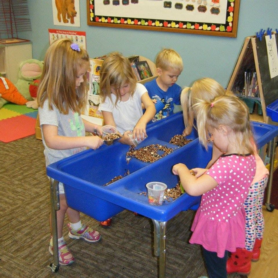 Children playing at a sensory table with small objects