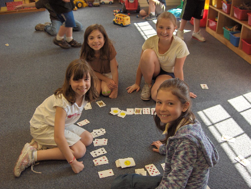 Four children playing cards on the floor