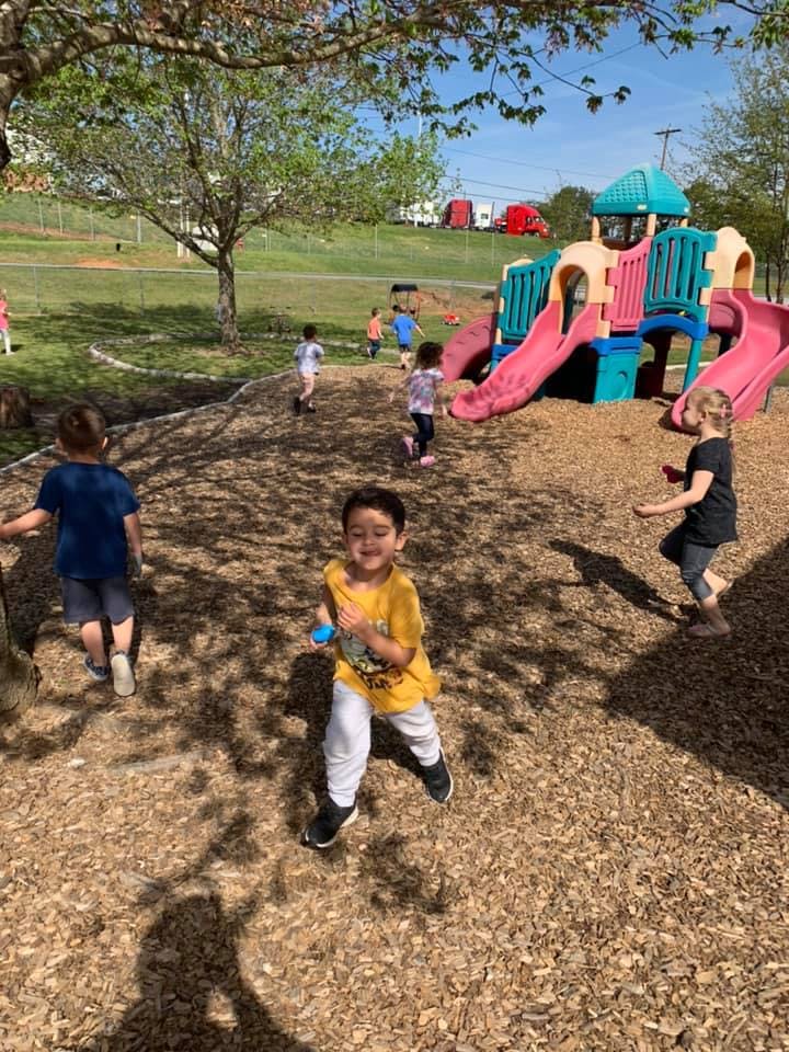 Children playing on a wood chip playground with a colorful playset