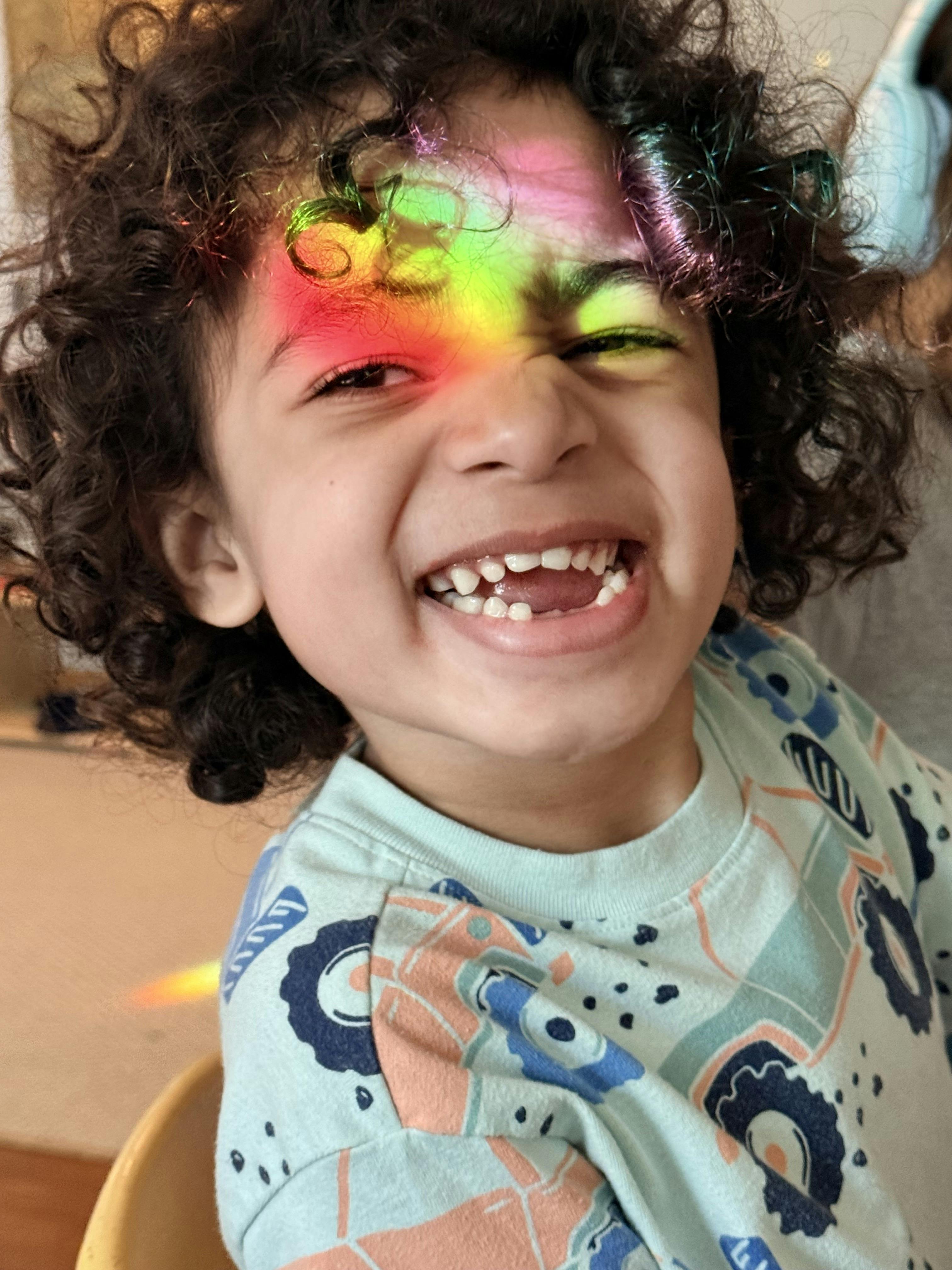 Child smiling with a rainbow of colors on their face