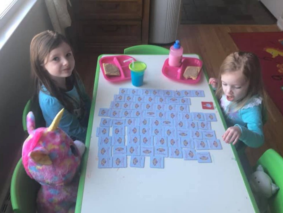 Two children at a table with cards and food