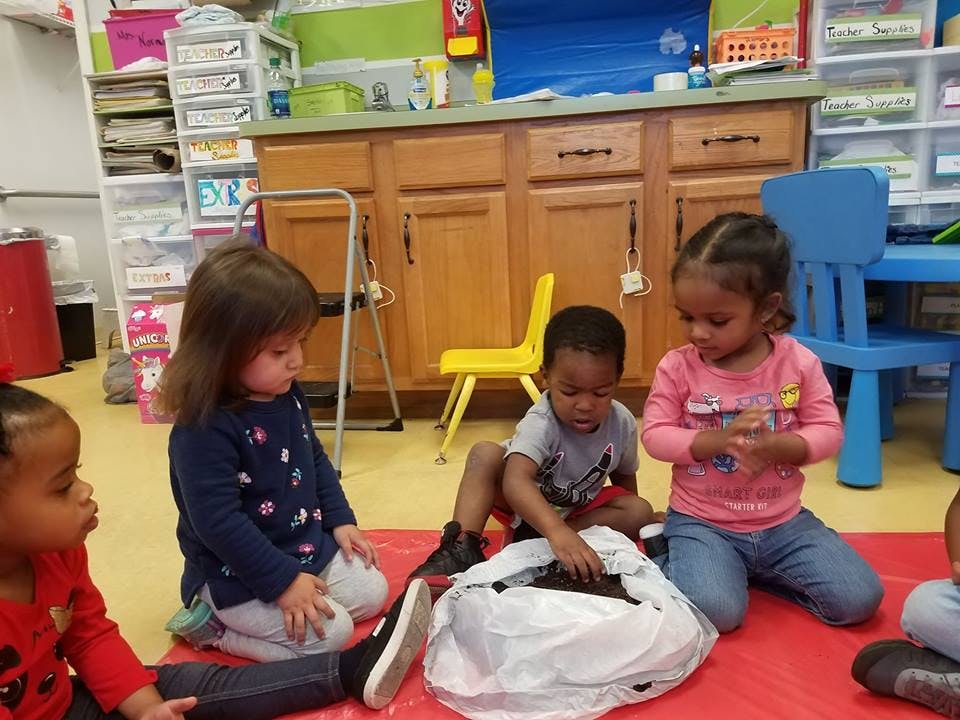 Children sitting on a red mat in a classroom