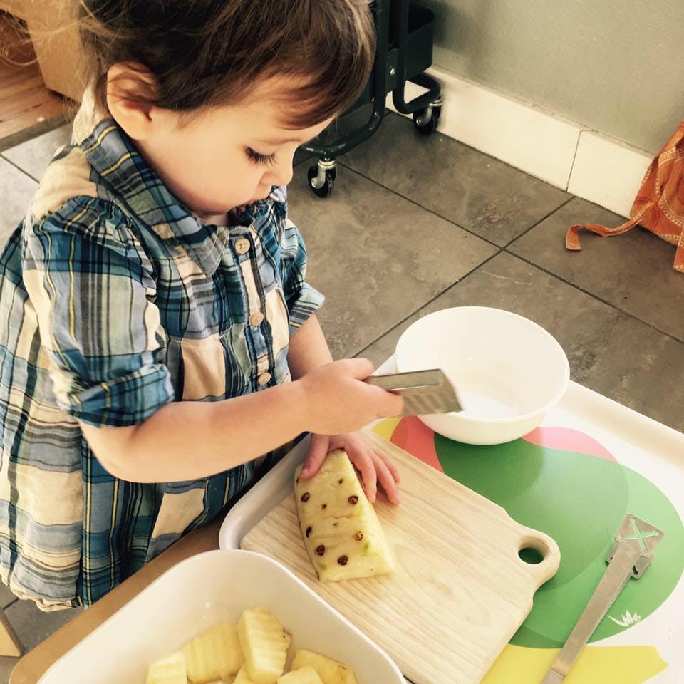 Child cutting fruit on a cutting board