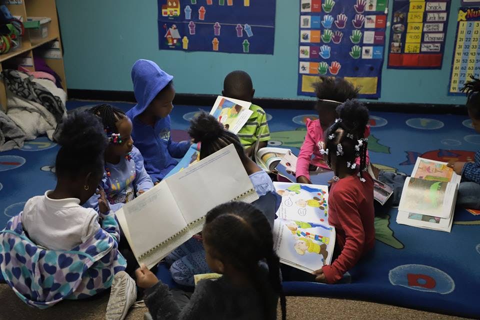 Children sitting on the floor reading books in a classroom