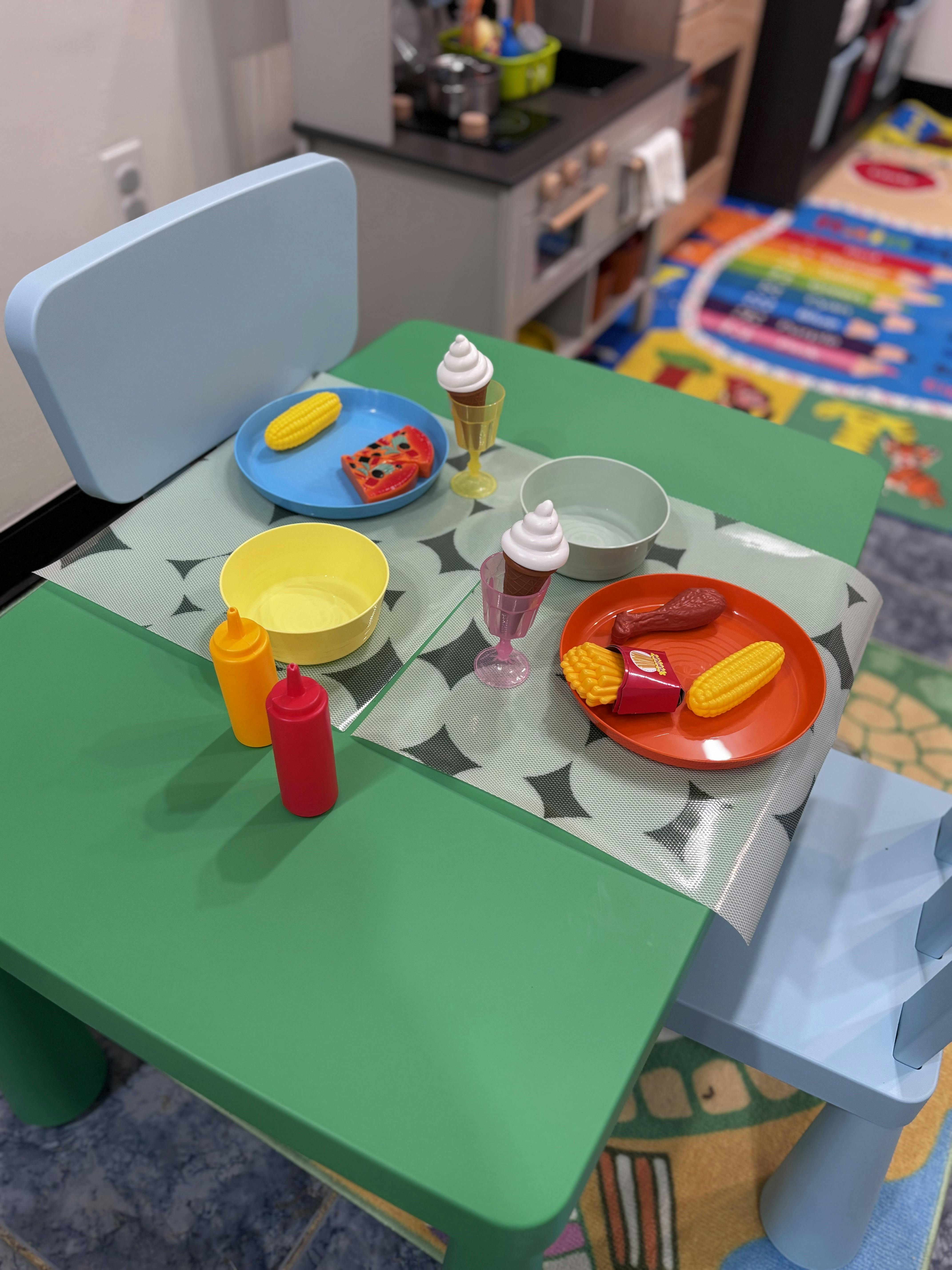 Plastic play food and toy plates arranged on a small children table