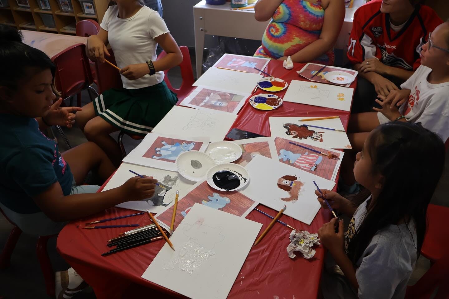 Several children painting at a table in a classroom