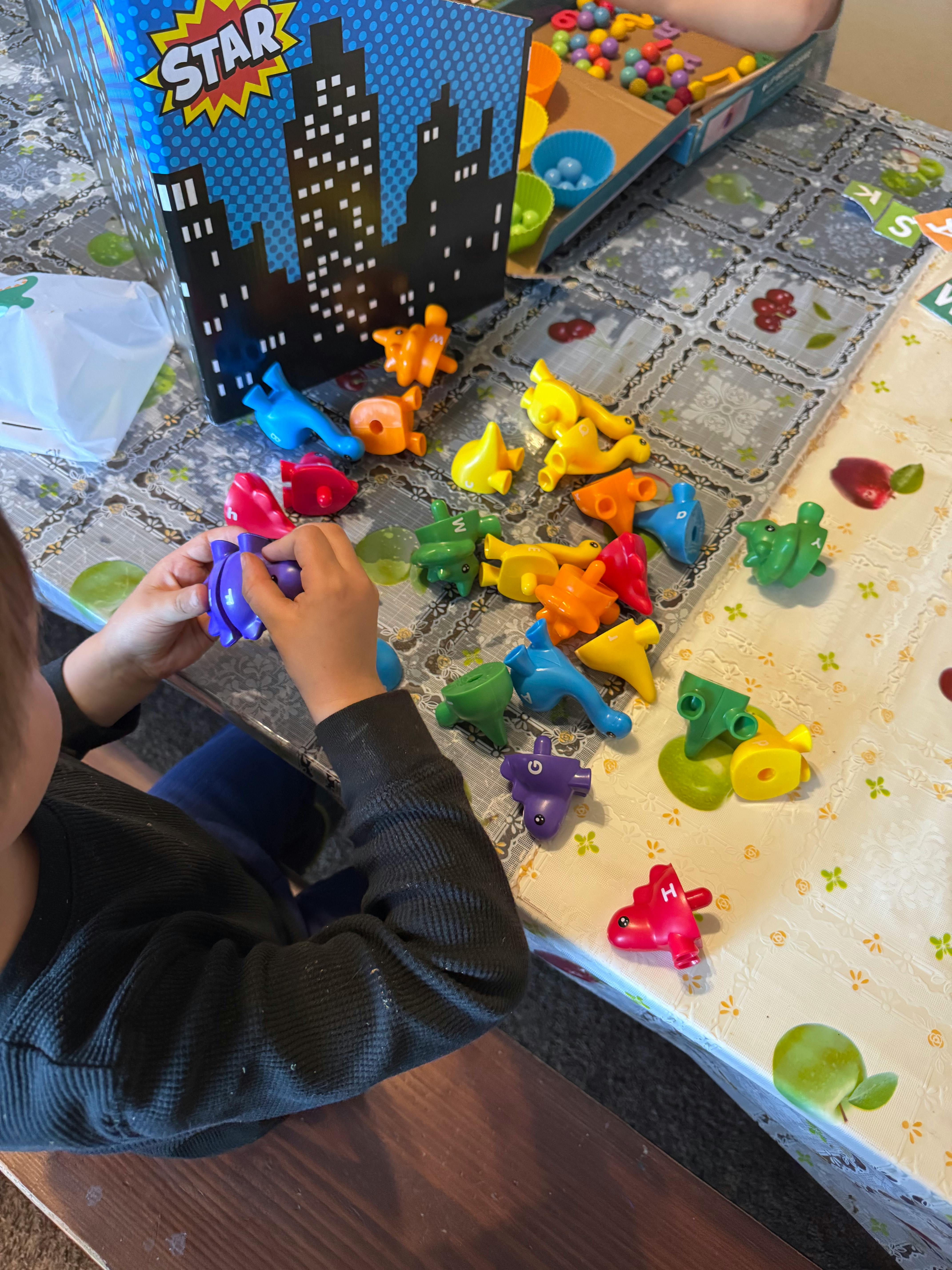 Child playing with colorful plastic animal toys on a table