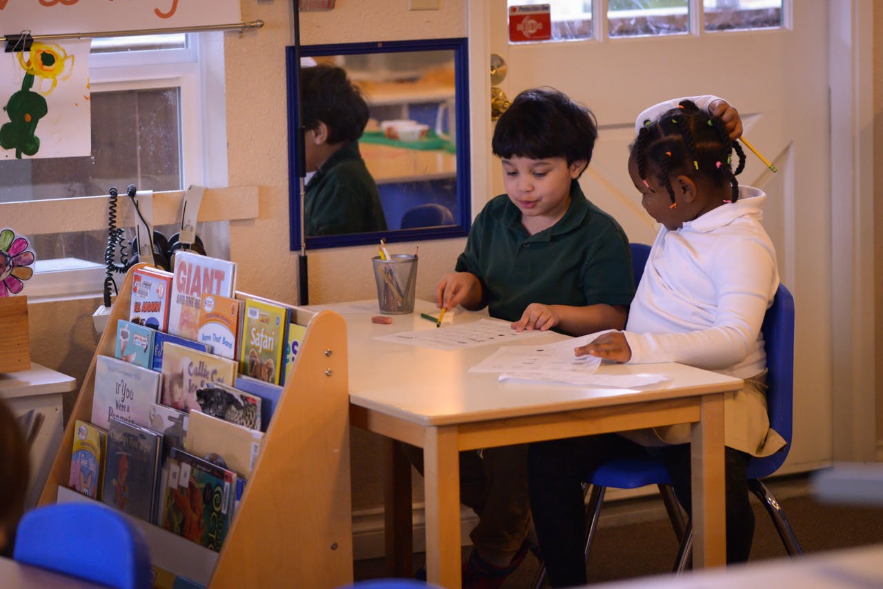 Two children sitting at a table in a classroom