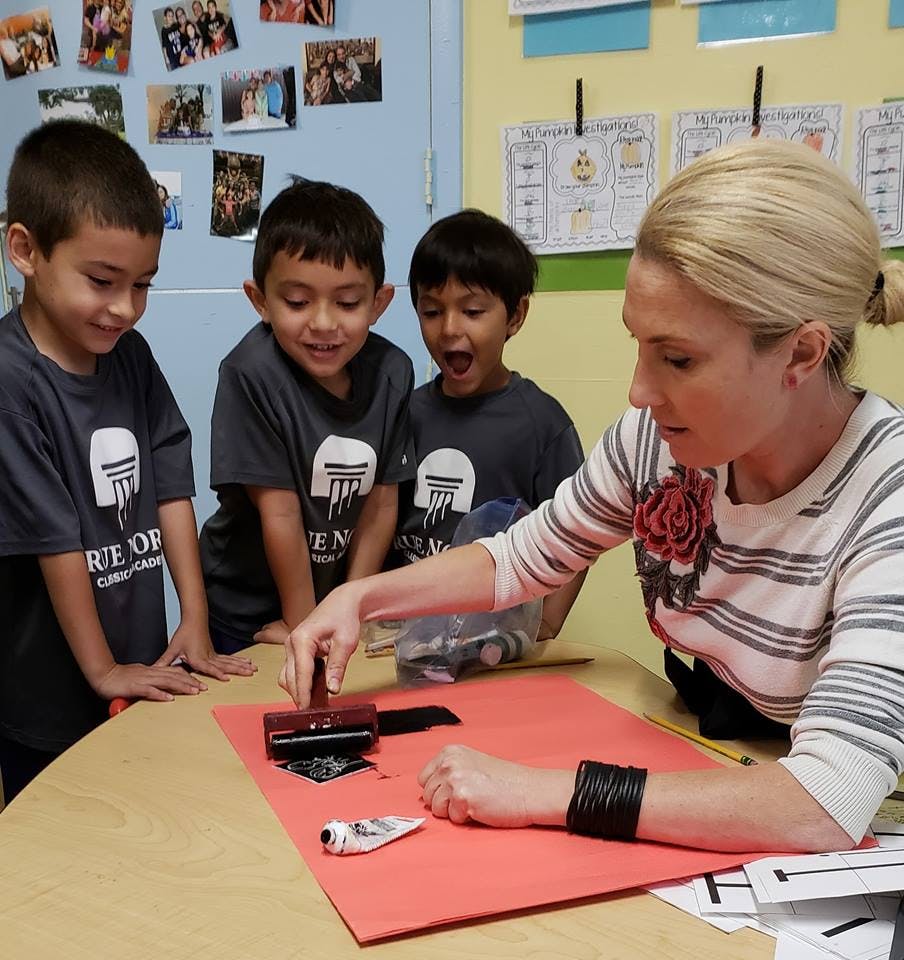 Adult and three children doing an art project with a roller and brayer
