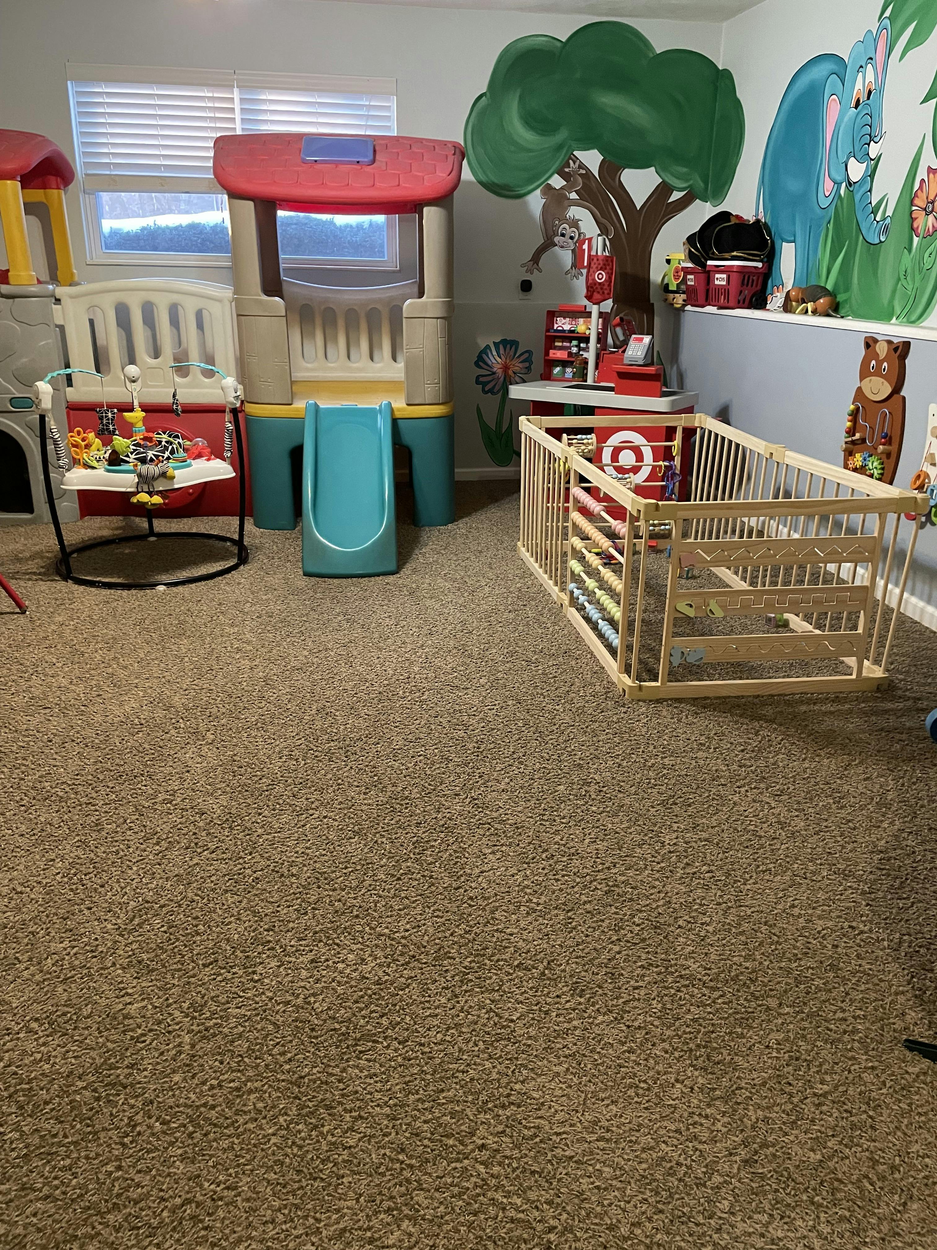 Indoor playroom with toy structures, playpen, and window blinds