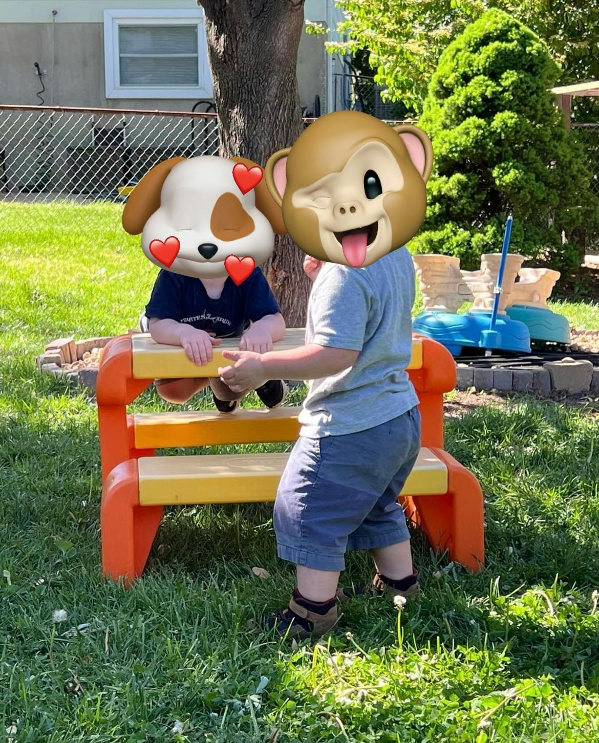Two children playing at a small picnic table outdoors