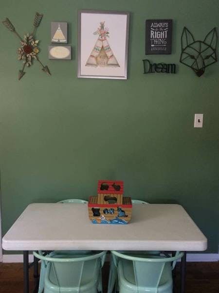 Table with a toy boat and chairs, wall decor above with framed art and decor