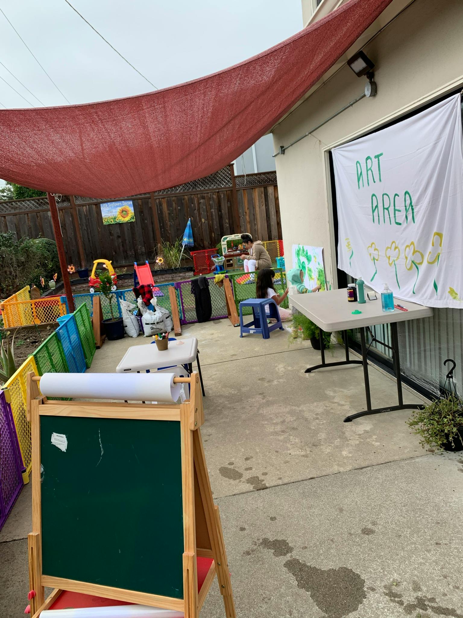 Outdoor art area with tables, easel, and a person in the background