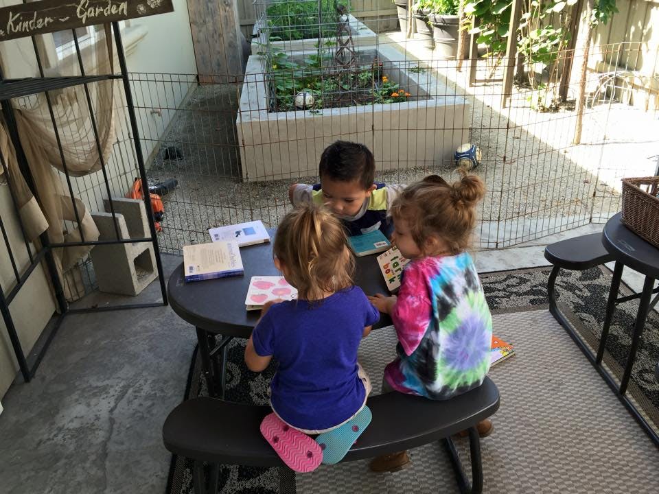 Three children sitting at a table with books and cards