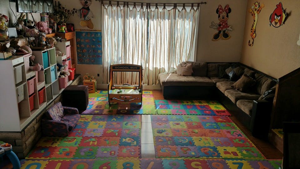 Playroom with colorful alphabet floor mats, shelves, and a sofa