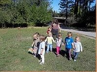 Adult and several children walking on grass