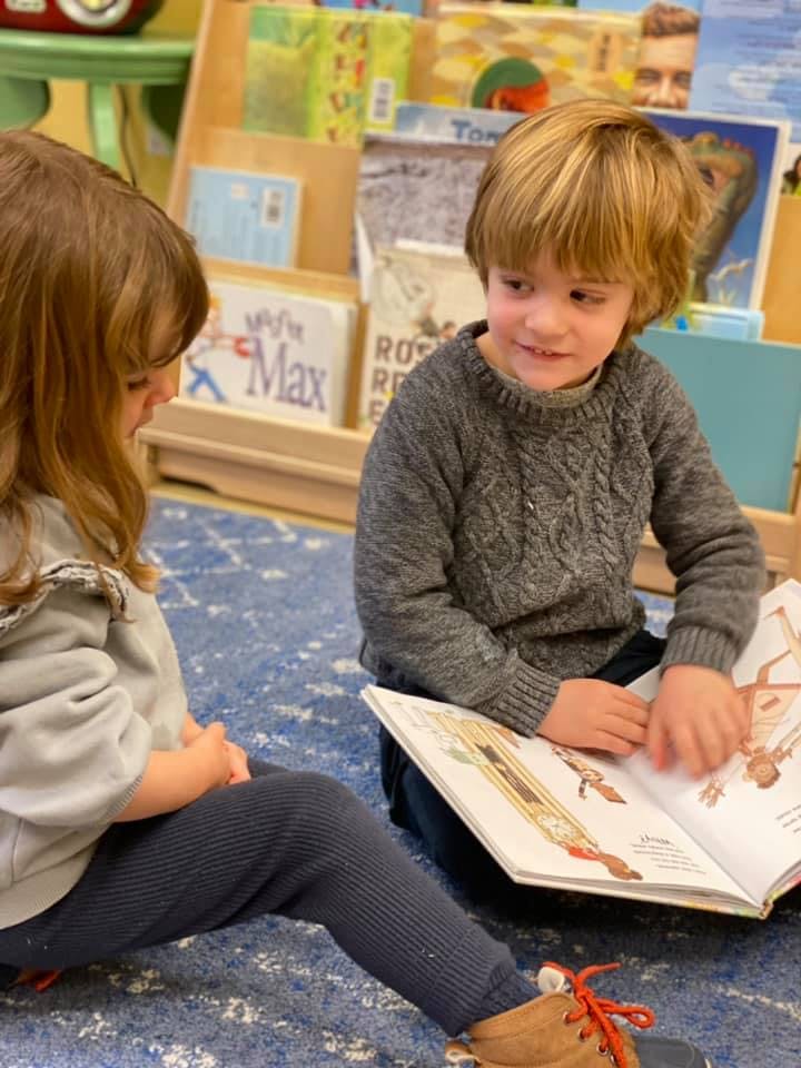 Two children sitting on the floor reading a book