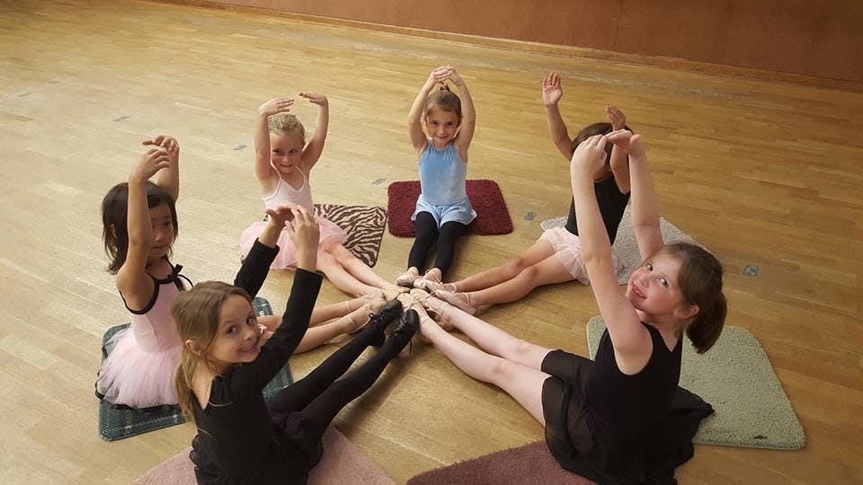 Children sitting in a circle with arms raised