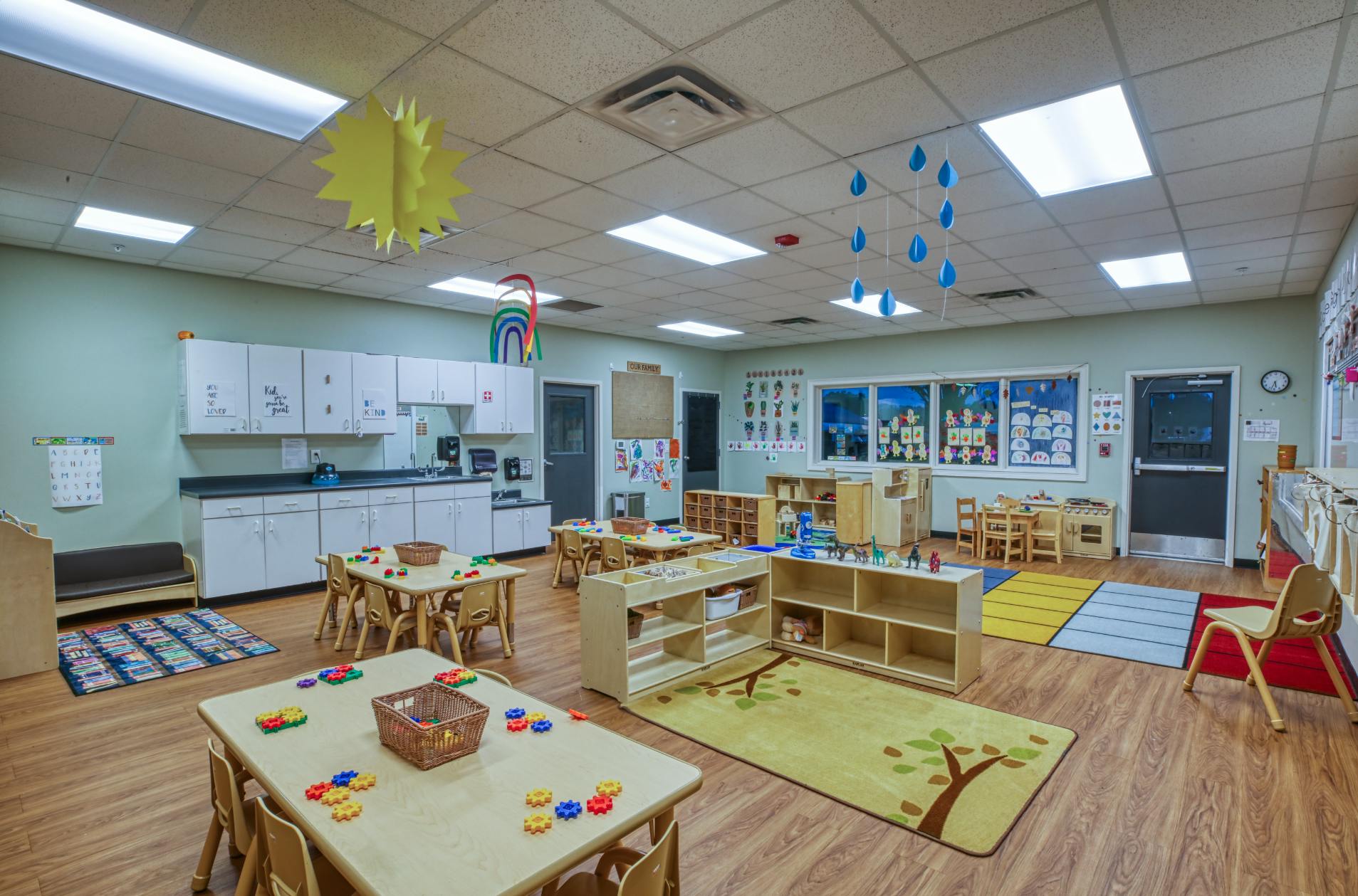 Empty classroom with small tables and chairs, toys, and cabinets