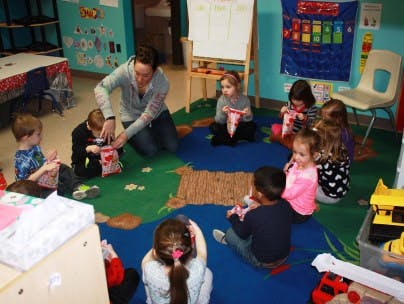 Adult and children sitting on a rug in a classroom