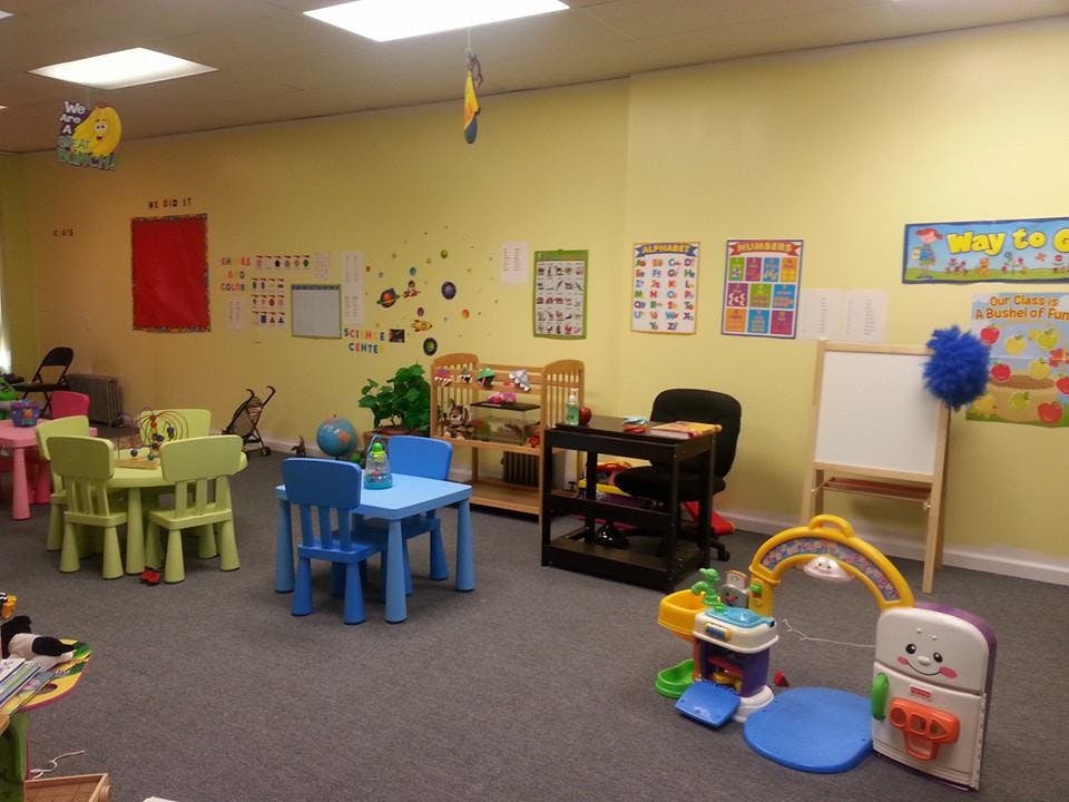 Classroom with small tables and chairs, educational posters on walls, and toys