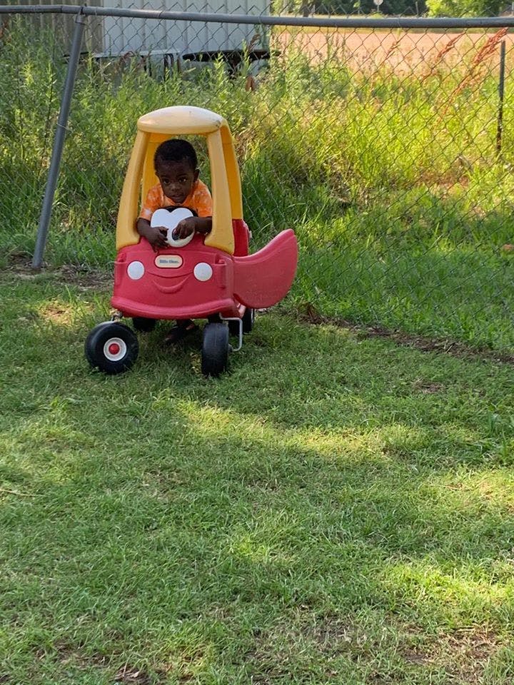 Child in a toy car on grass