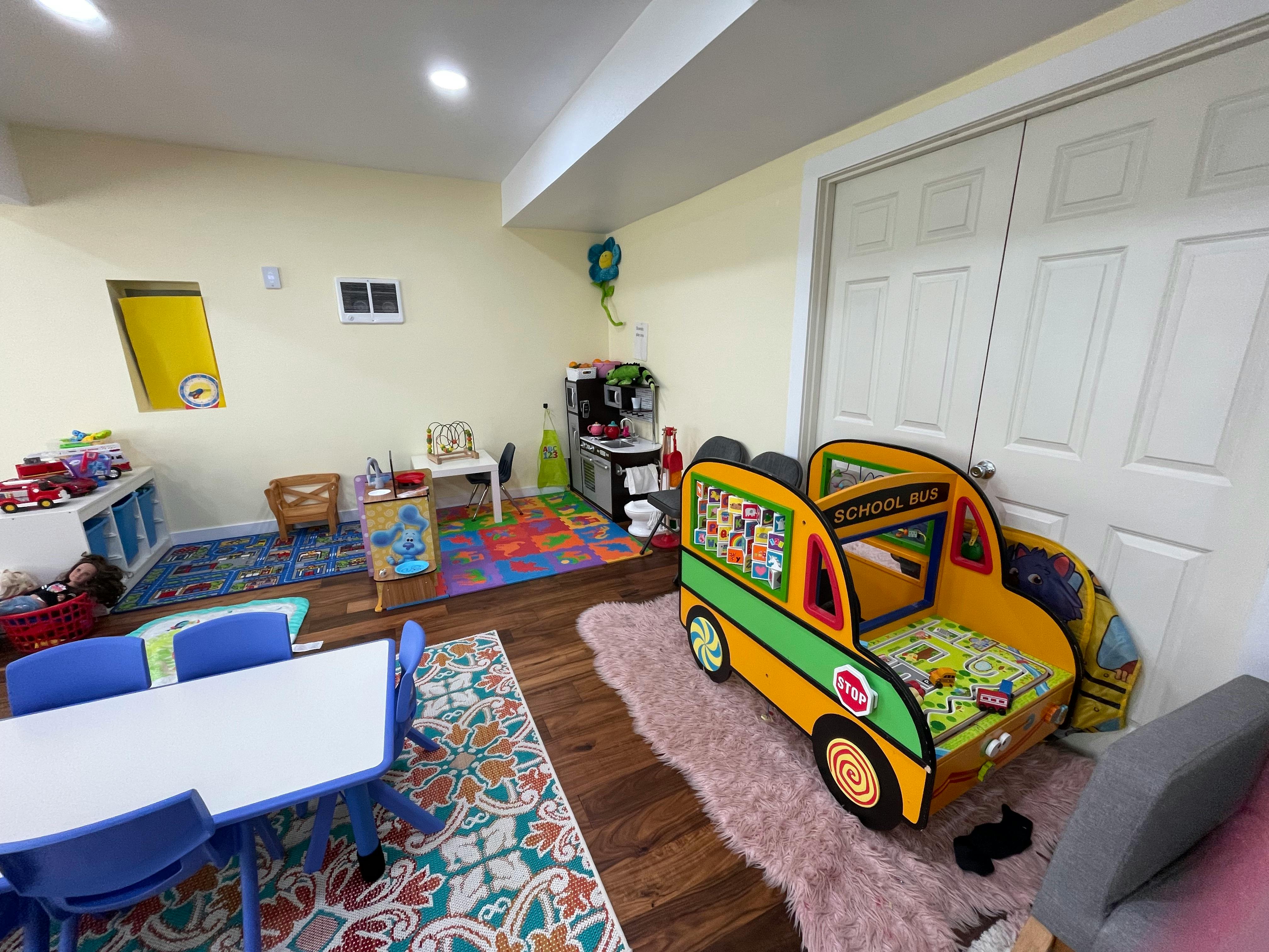 Playroom with a school bus bed, small tables, and colorful rugs