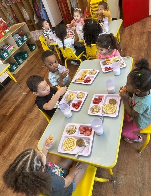 Group of children eating lunch at tables in a classroom
