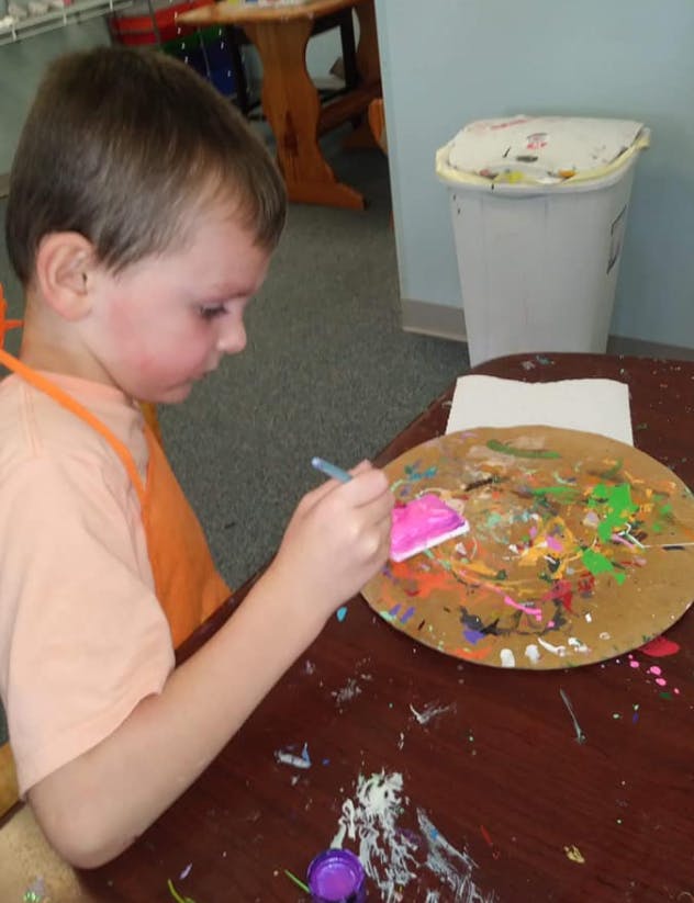 Child painting on a round palette with a brush