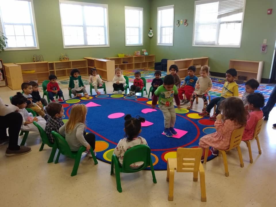 Children sitting in a circle on a colorful rug in a classroom