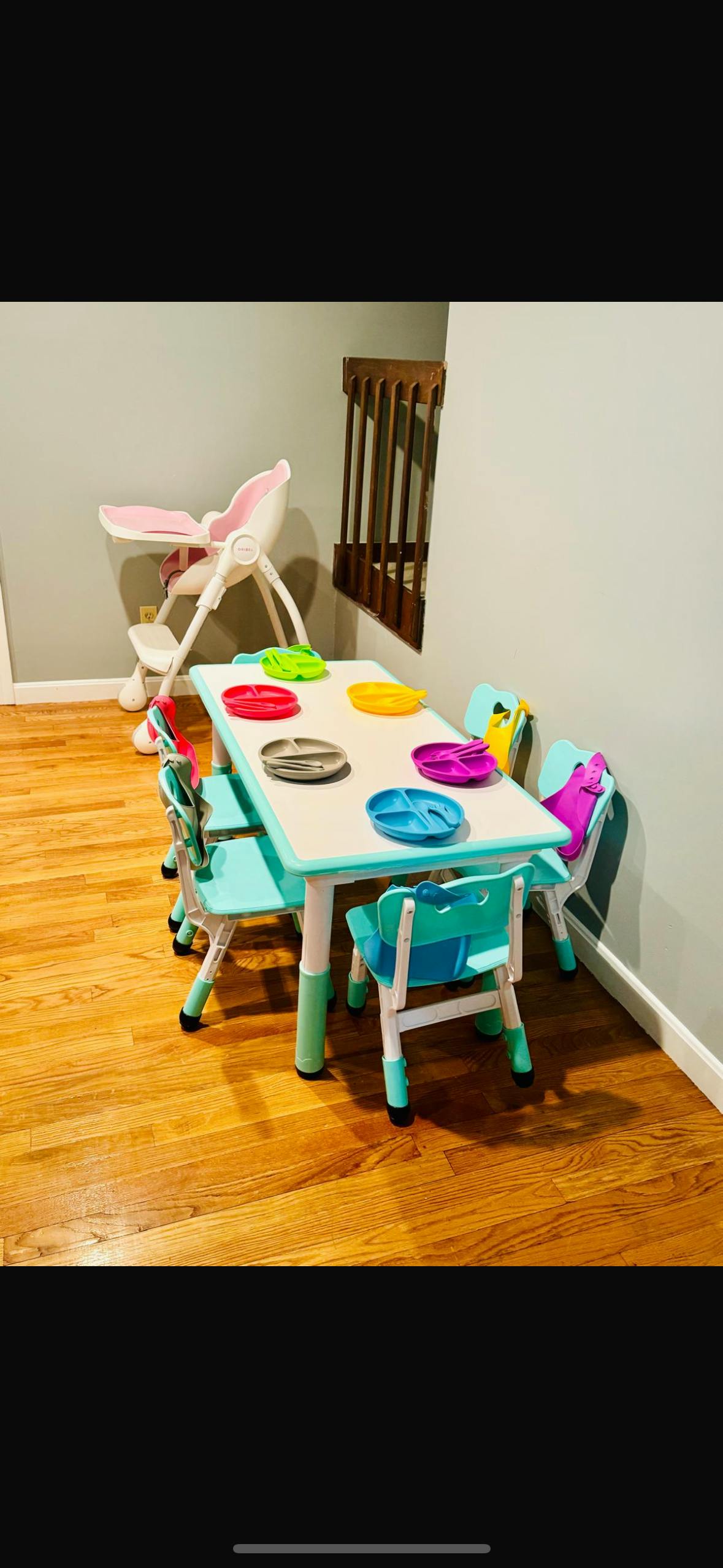 Child-sized table with colorful plates and chairs, with a high chair nearby