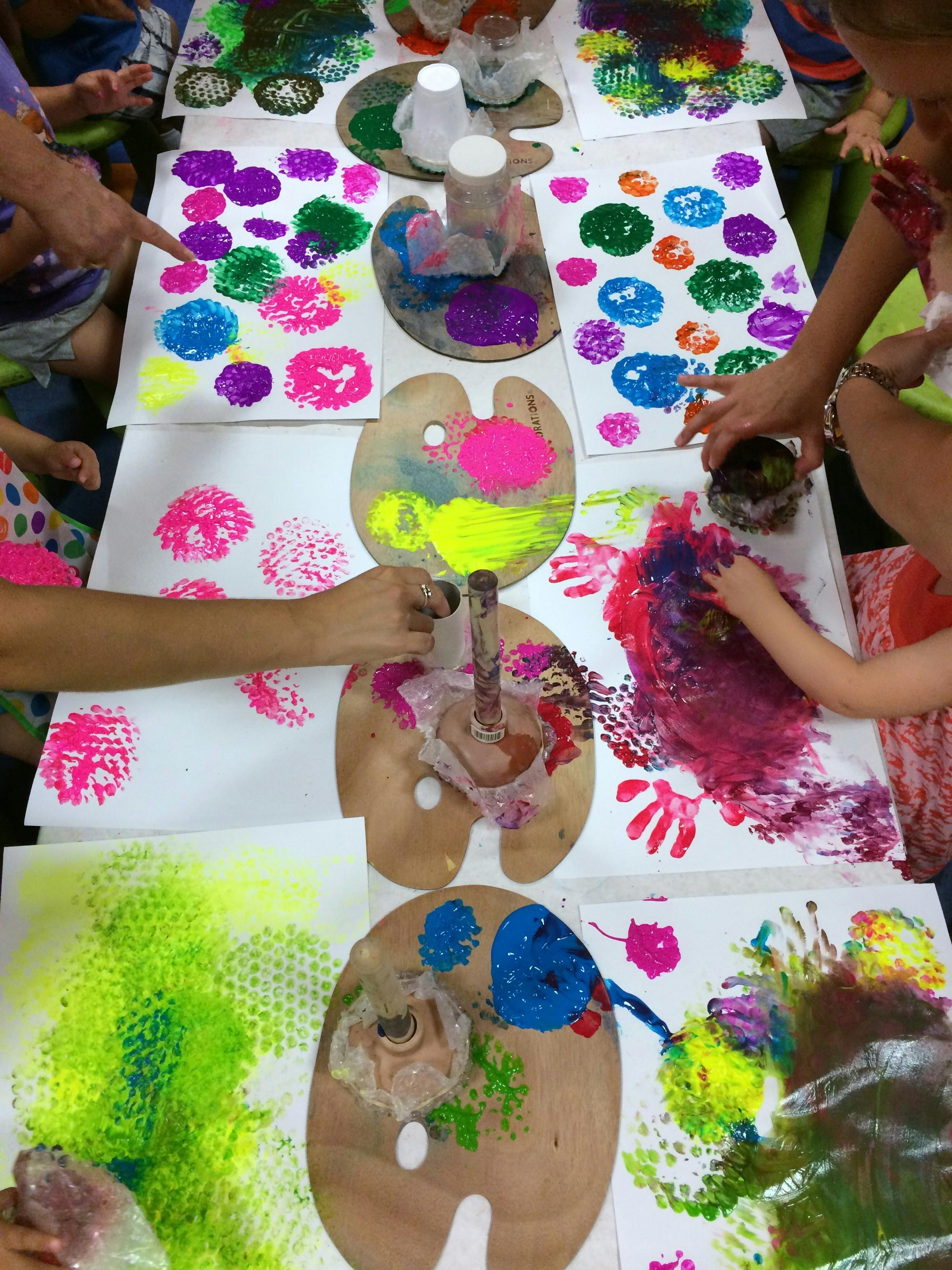 People painting with colorful paints and sponges on white paper