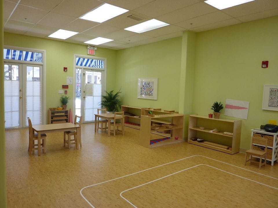 Empty classroom with small tables, chairs, and shelves