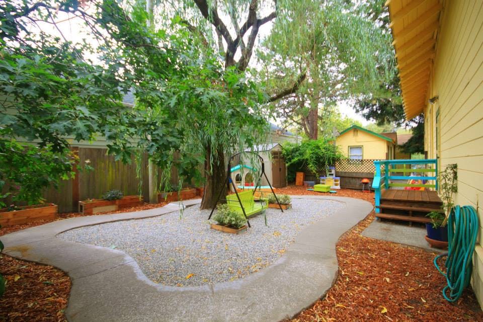 Backyard with a gravel play area, swing set, and wooden deck