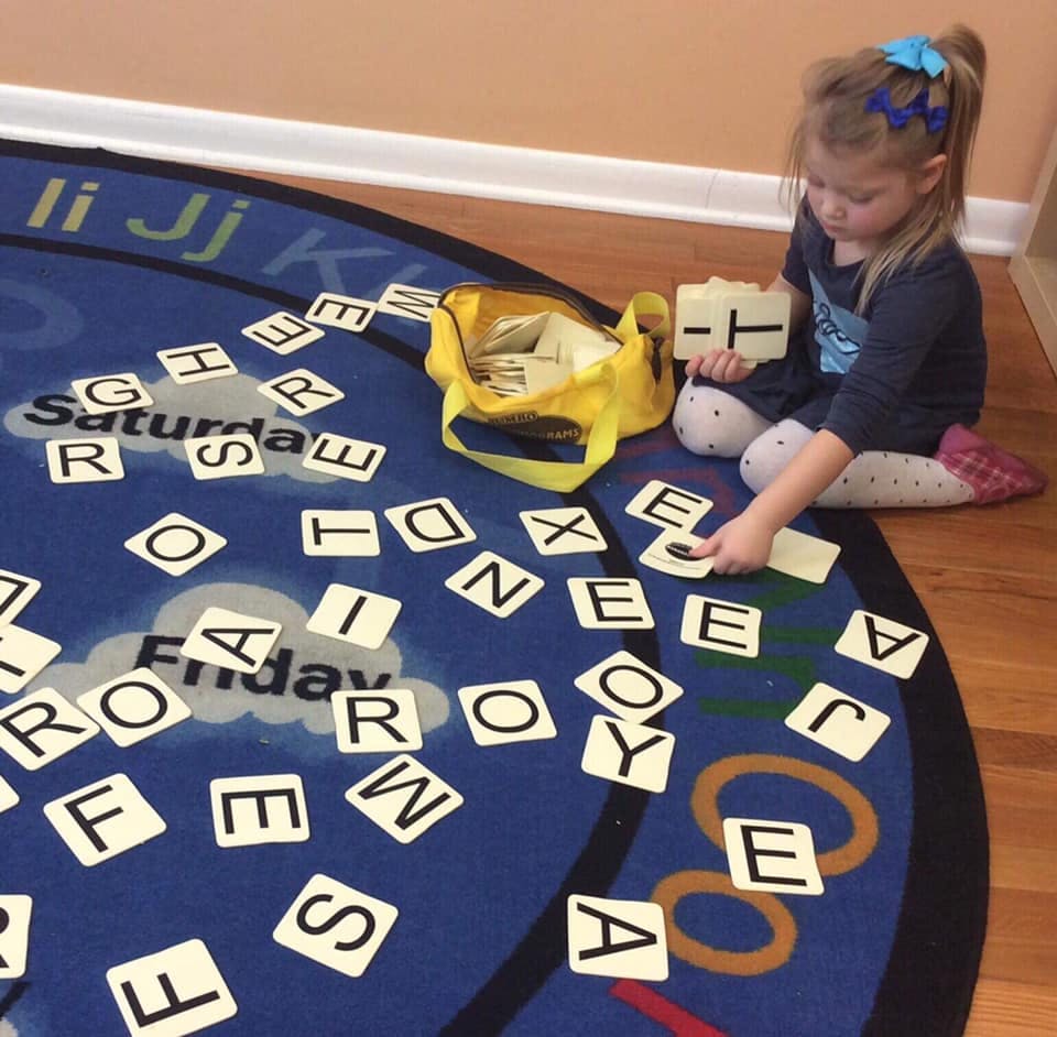 Child playing with letter tiles on a rug