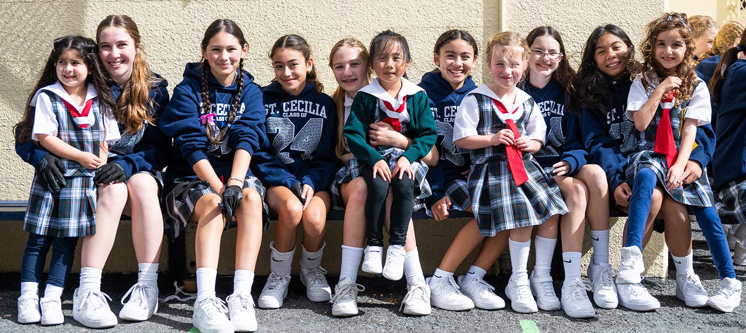 Group of children and teens in school uniforms sitting on a bench