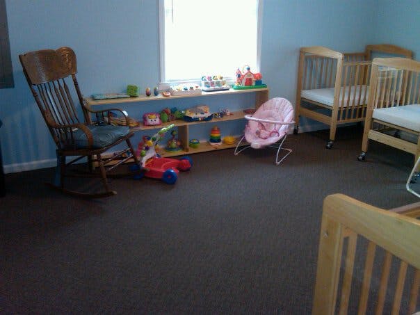 Nursery room with cribs, rocking chair, and shelves with toys