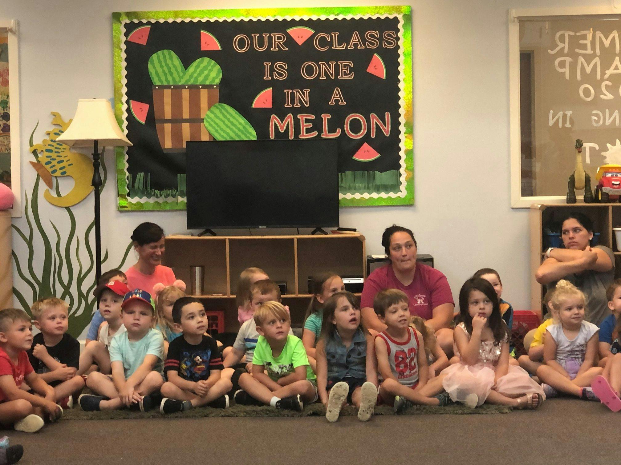 Adults and children sitting on the floor in a classroom