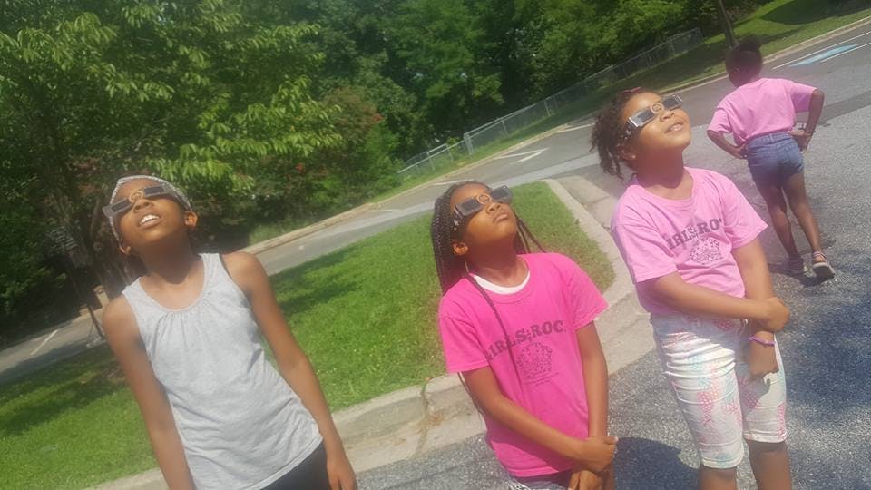 Three children wearing sunglasses looking up