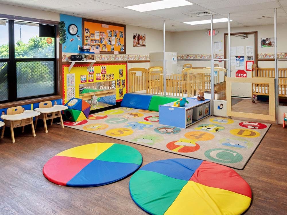 Playroom with cribs, play mats, and small tables