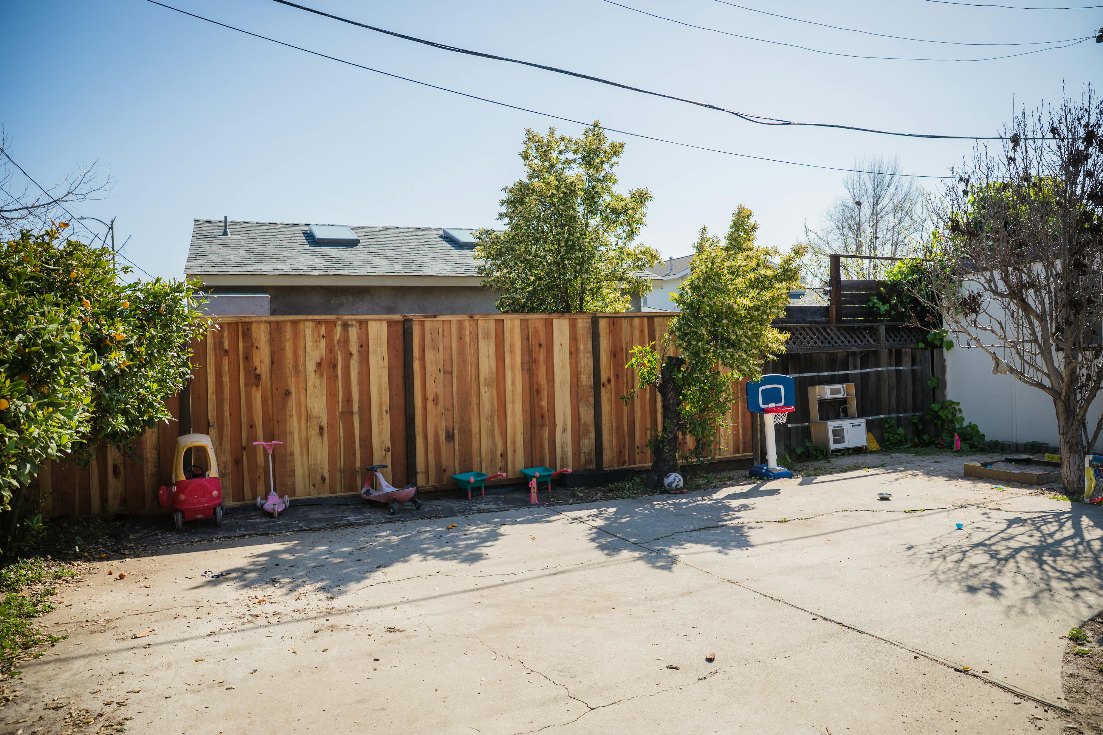 Backyard with a wooden fence, children's toys, and a basketball hoop