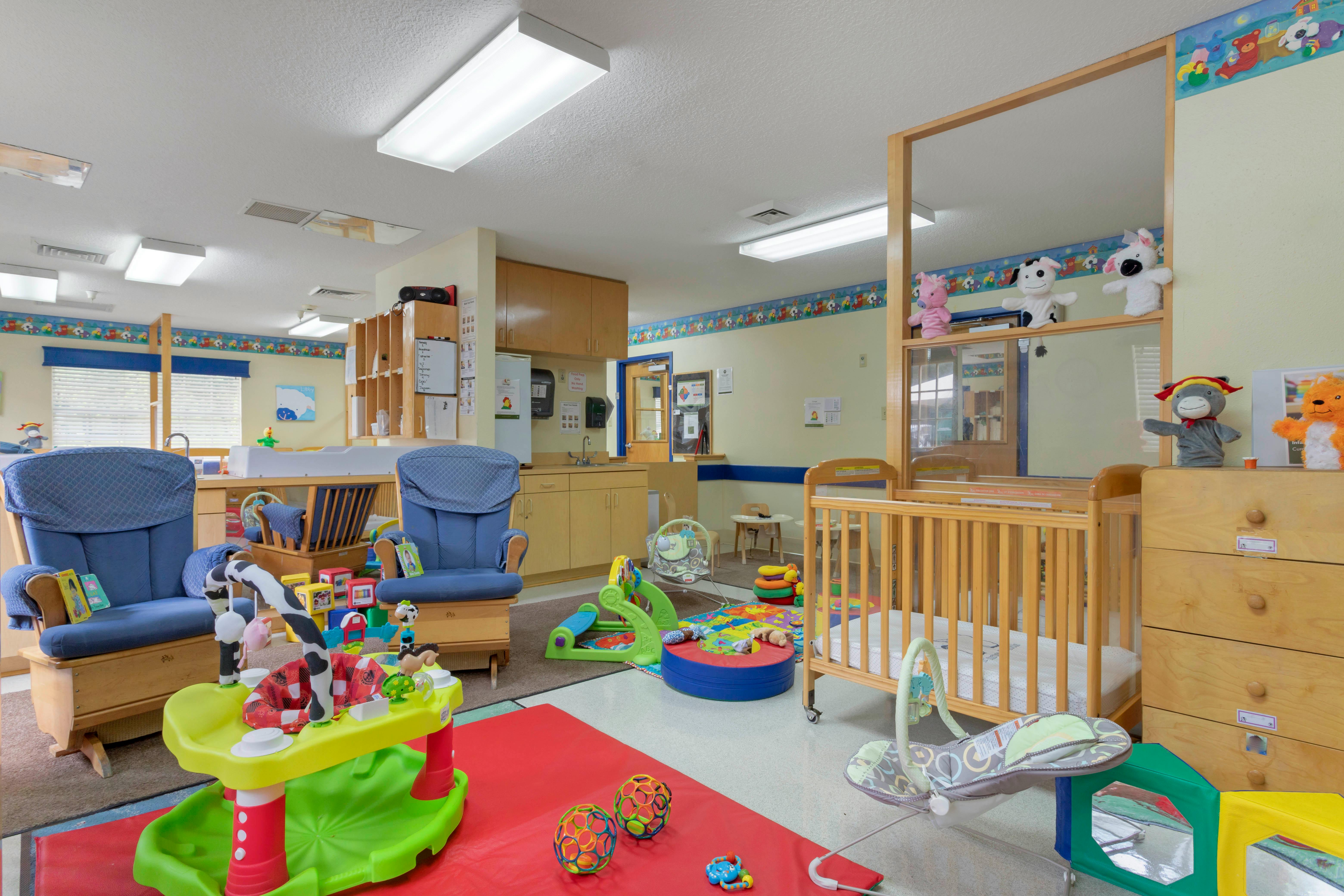 Baby and toddler play area with cribs, chairs, and various toys