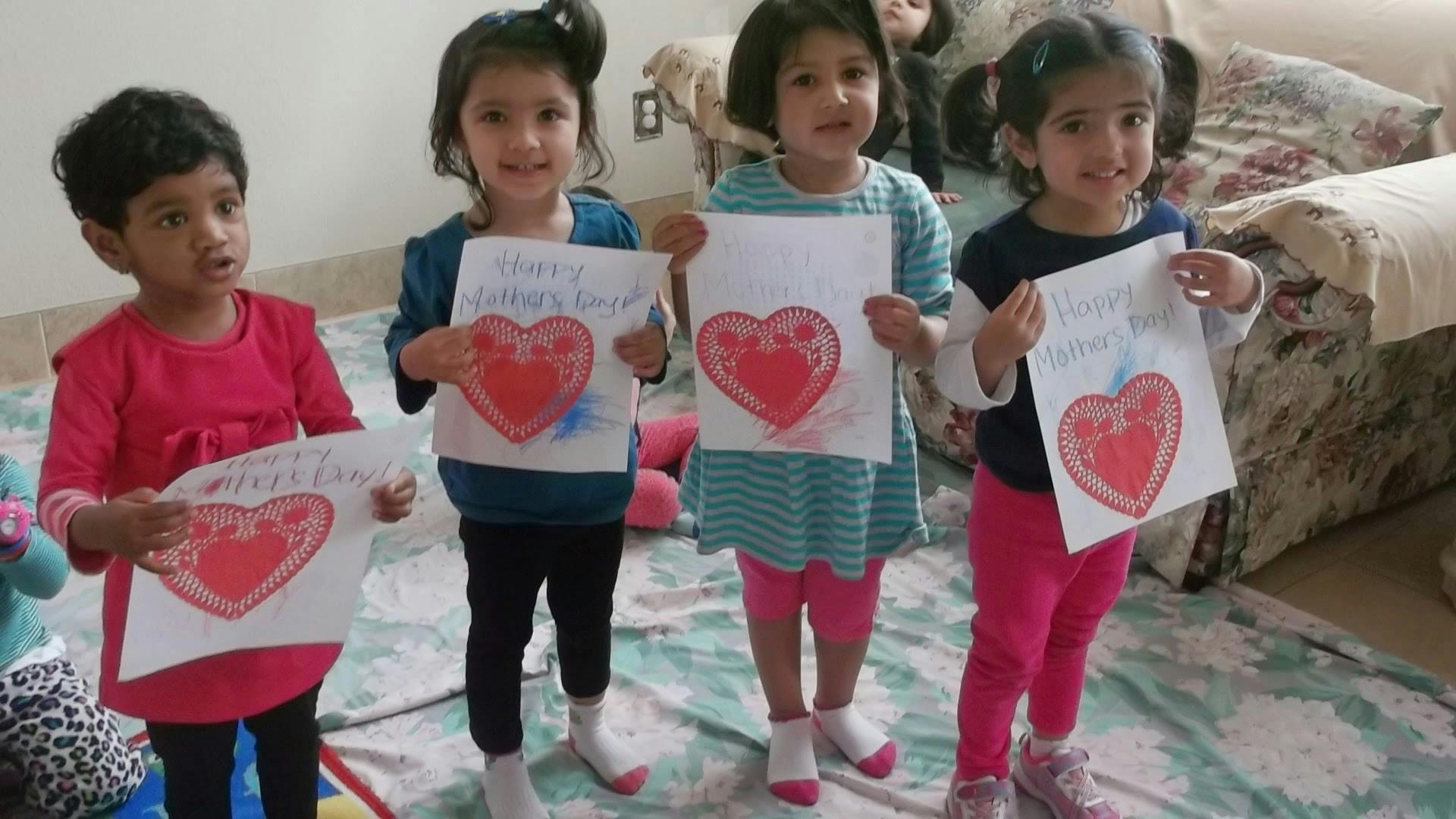 Four children holding up drawings of hearts