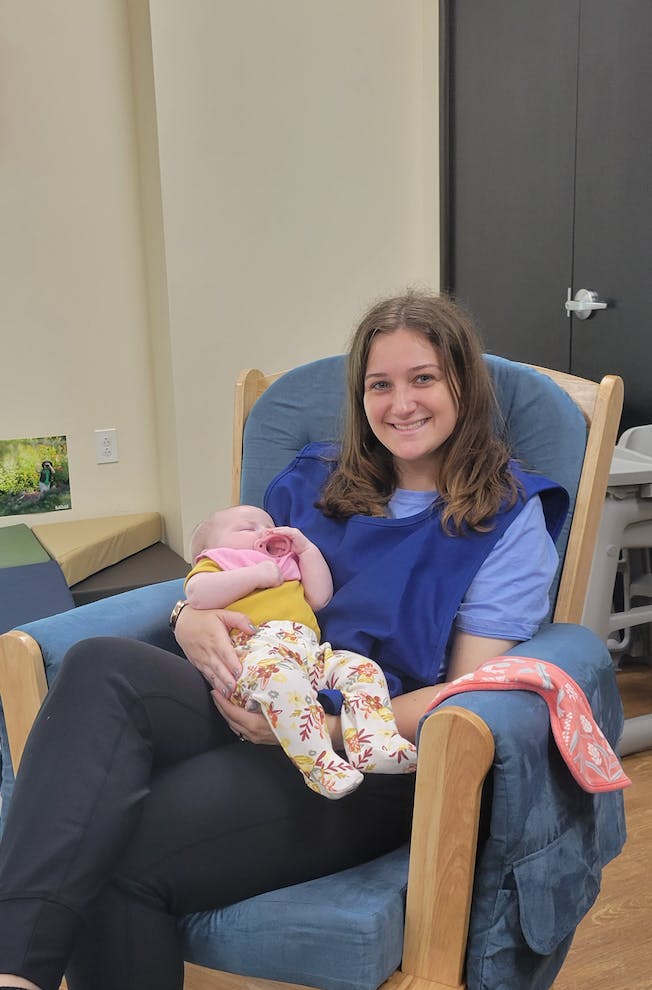 Person sitting in a chair holding a sleeping infant