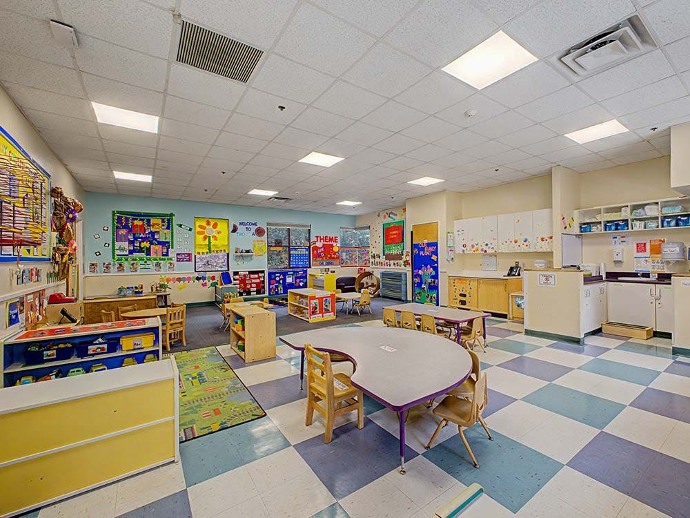 Empty colorful preschool classroom with small tables and chairs